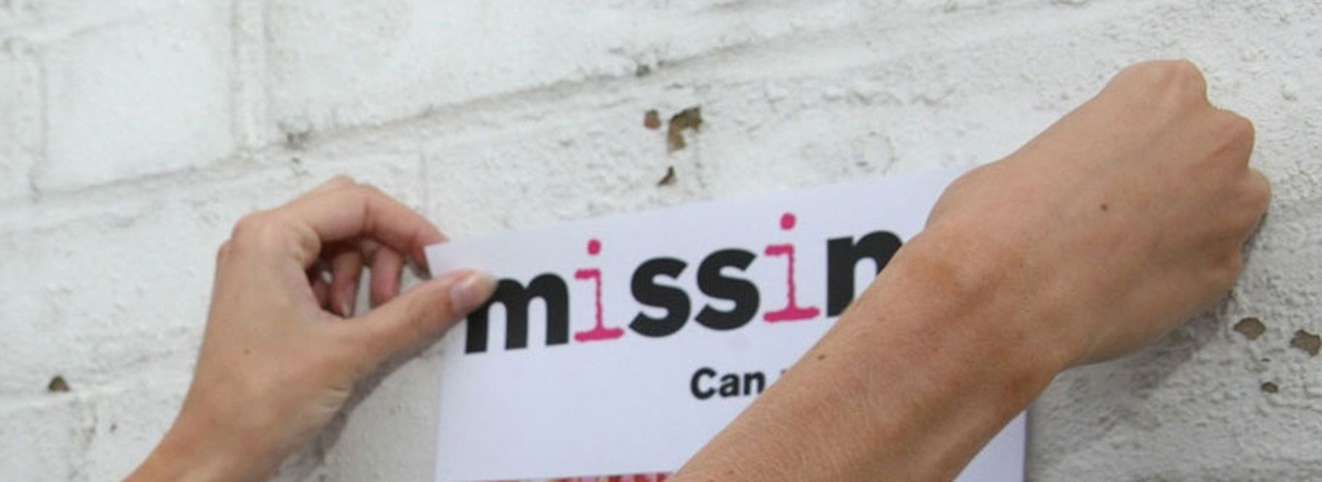 Close-up of hands putting up a Missing People poster